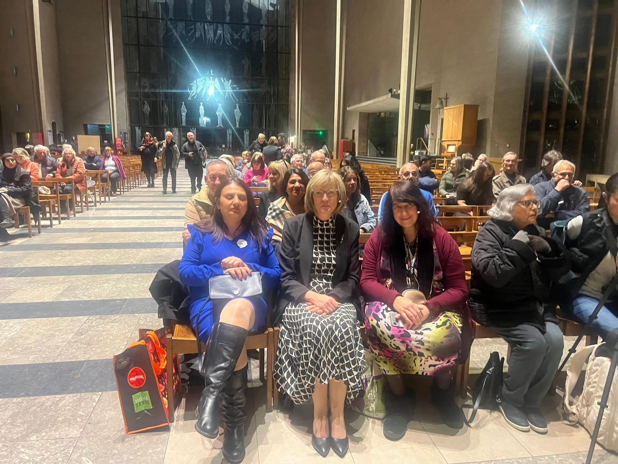 Community members seated together inside Coventry Cathedral
