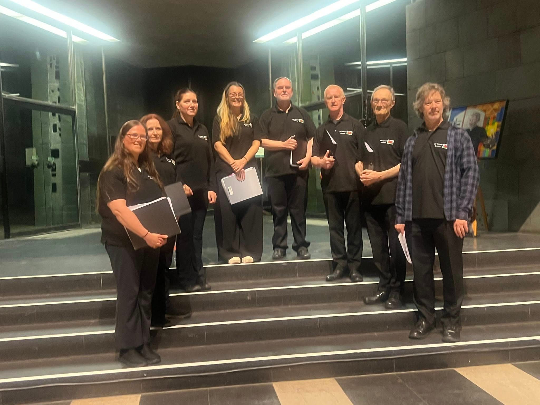 A volunteer team standing together on the steps inside Coventry Cathedral