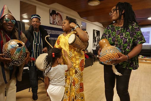 A family playing traditional drums and shekere gourds at a Coventry Diversity Forum cultural event